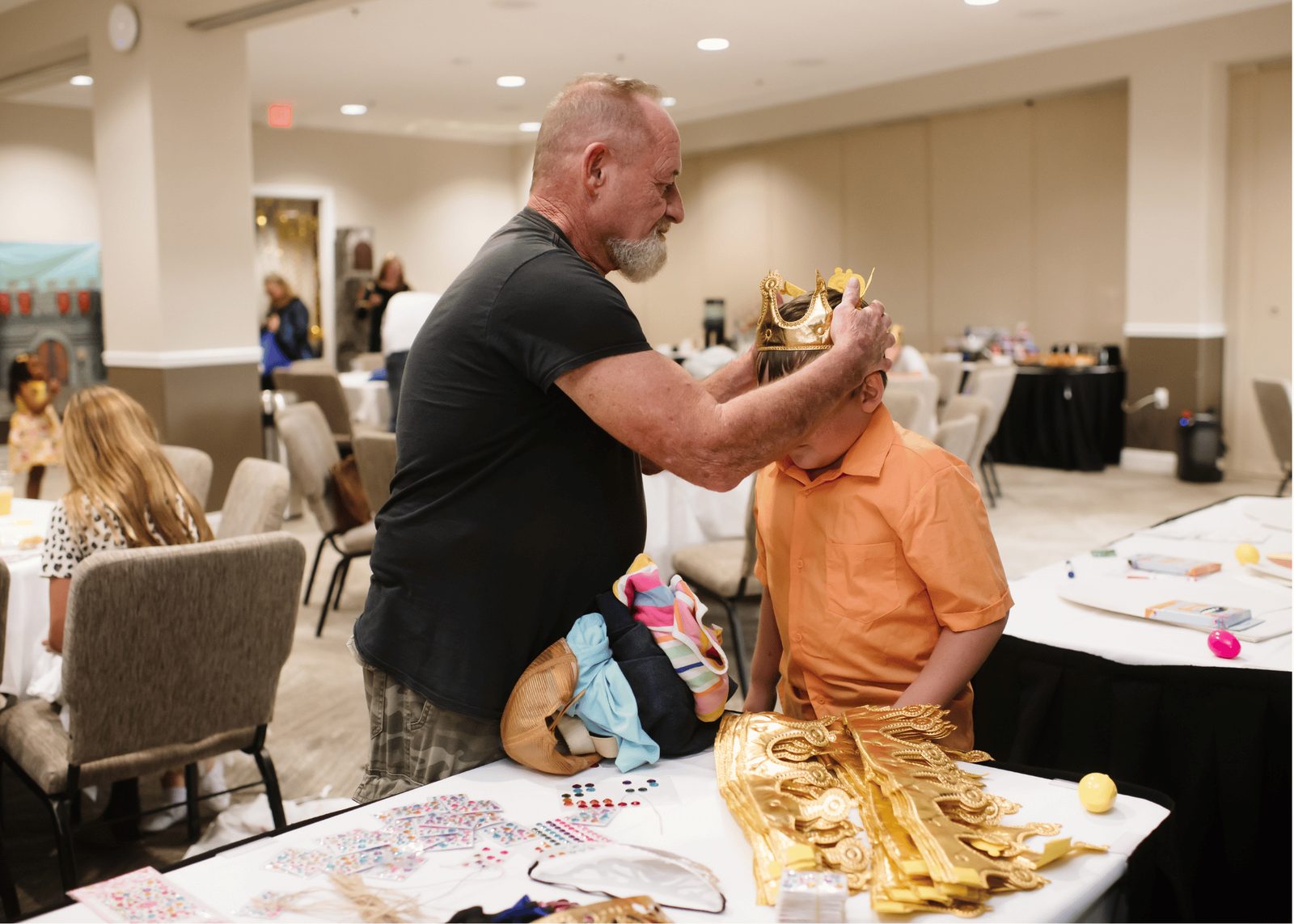 A father places a gold paper crown on his son's head.